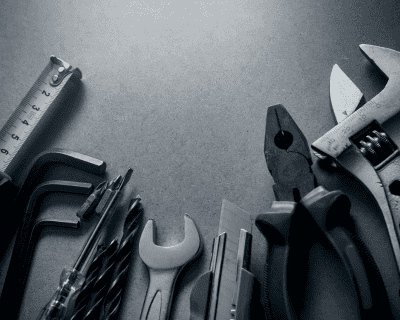 Assorted hand tools arranged on a gray surface.