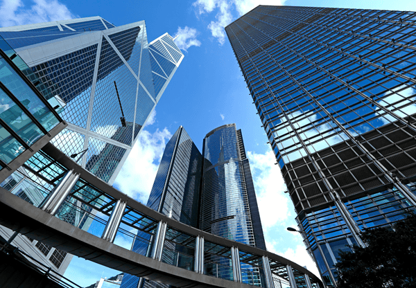 Modern glass skyscrapers with a pedestrian bridge in the foreground.