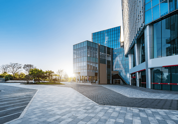 Moderne Bürogebäude mit Glasfassaden und gepflastertem Innenhof.