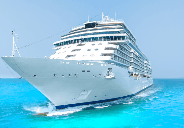 A large white cruise ship sailing in clear turquoise waters.