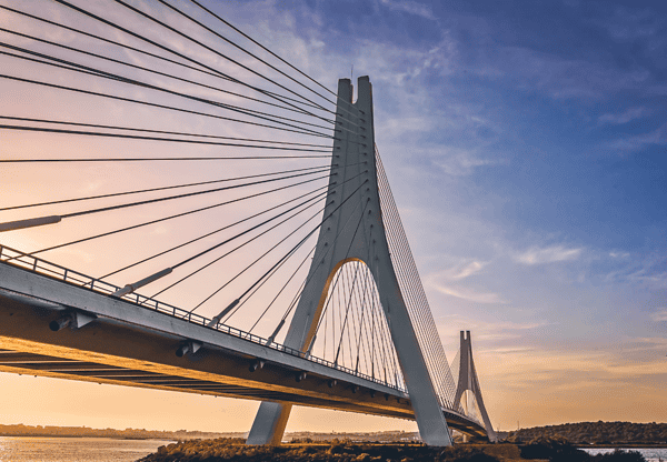 A modern cable-stayed bridge at sunset.