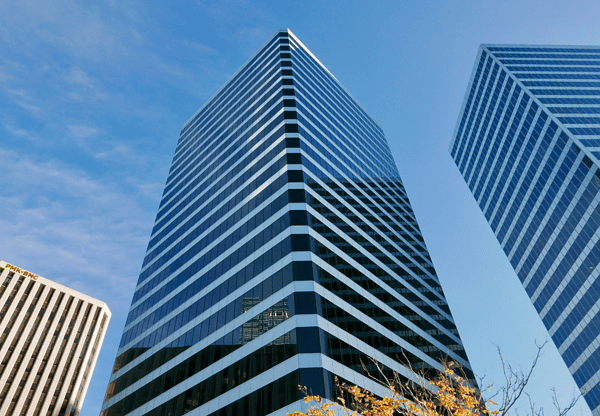 Upward view of a modern glass office building against a clear sky.