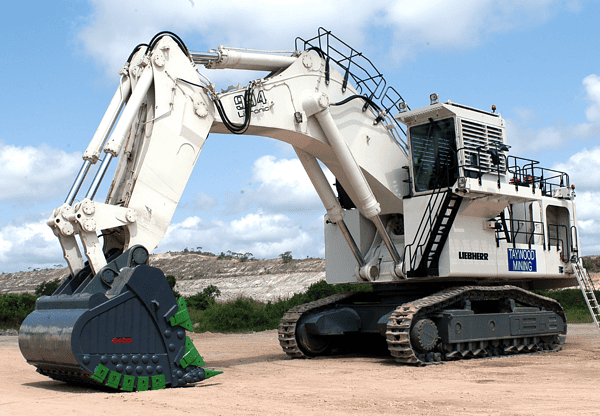 A large white excavator parked on a dirt surface.