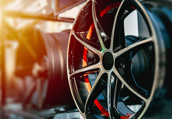 Close-up of car rims displayed in a row with sunlight reflecting off the metal.