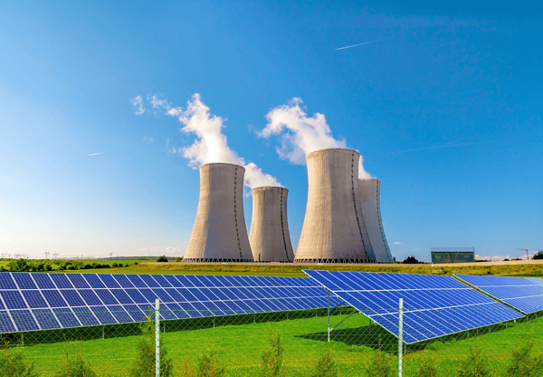 Solar panels in front of cooling towers at a power plant.