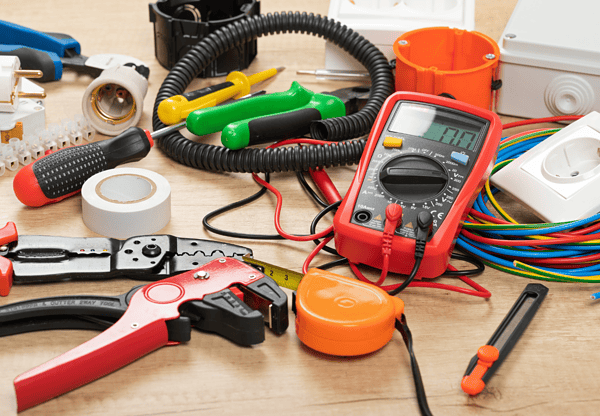 A collection of various electrical tools and devices on a workbench.