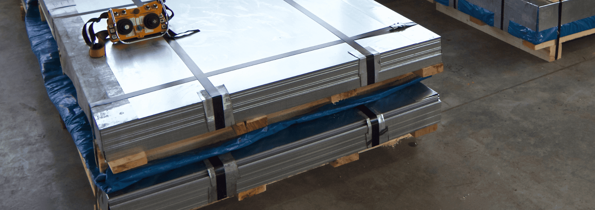 Stack of hot rolled steel bars on pallets, secured with straps and accompanied by testing equipment.