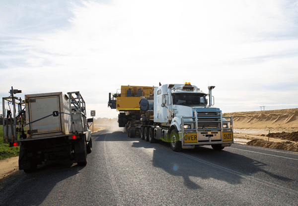 Heavy-duty trucks transporting equipment, highlighting the use of MN13 steel for high impact resistance.