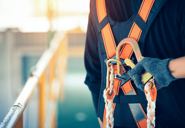 Worker wearing a safety harness and holding a carabiner.