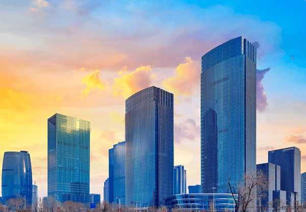 Modern skyscrapers at sunset, constructed with Q355B wind and solar steel, emphasizing durability and sustainability.