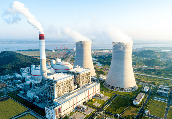 Aerial view of a power plant with large cooling towers emitting steam.