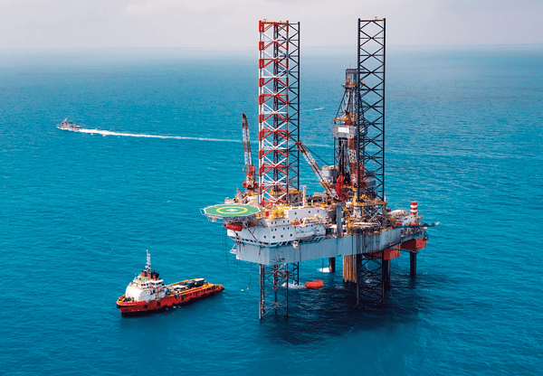 Offshore oil rig with a support vessel nearby in the ocean.