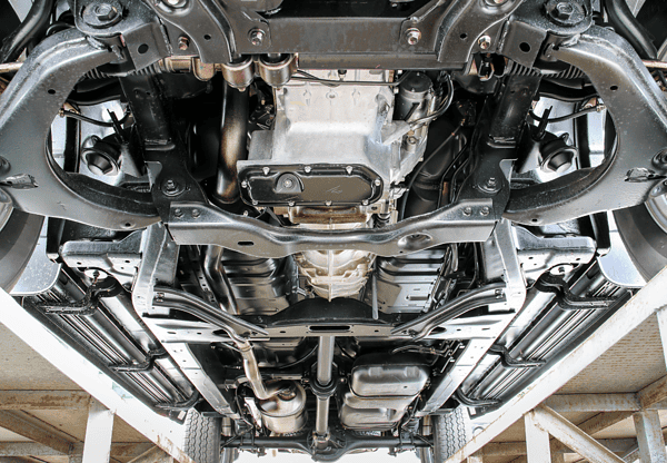 Underside view of a vehicle on a lift, showing mechanical components and structure.