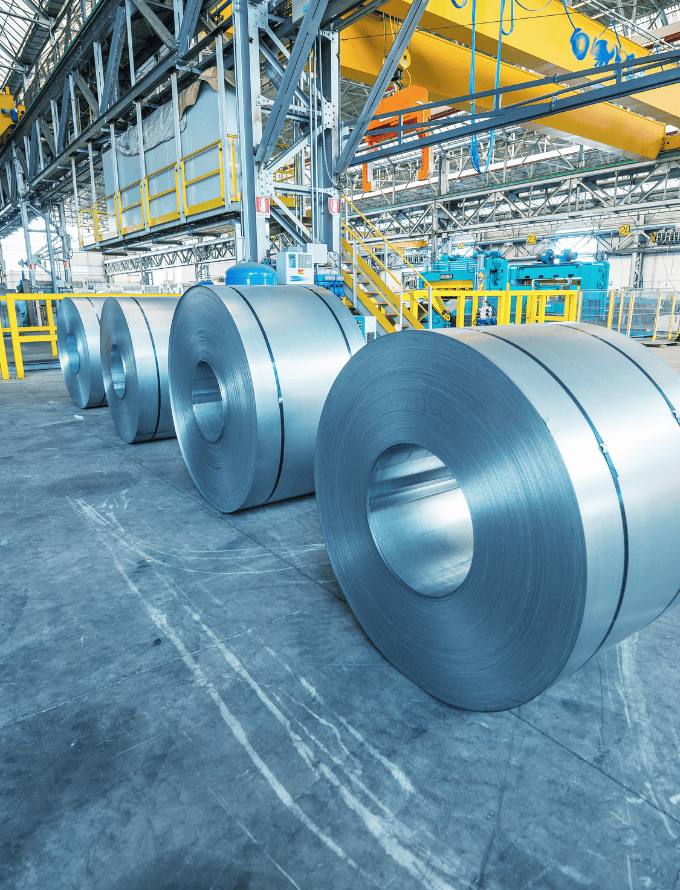 Large rolls of steel in an industrial warehouse.