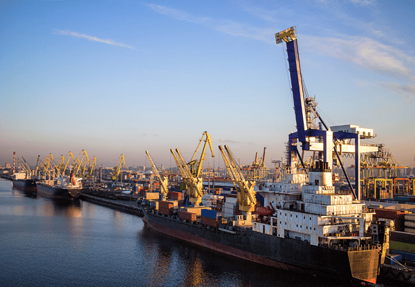 Cargo ships docked at a busy port with multiple cranes.