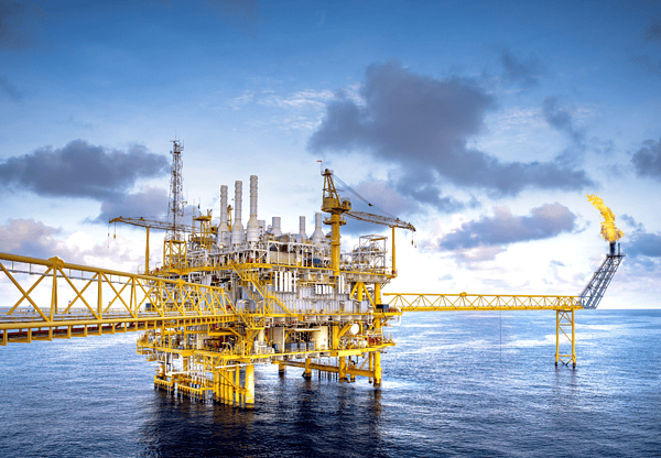 Yellow offshore oil platform with a flare stack burning against a cloudy sky.