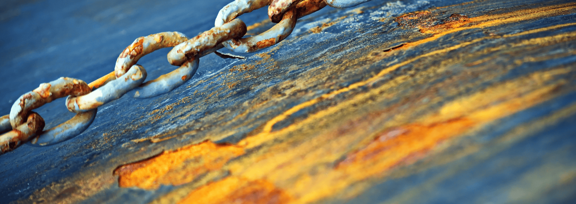 Rusty steel chain links on a weathered surface, showing signs of corrosion.