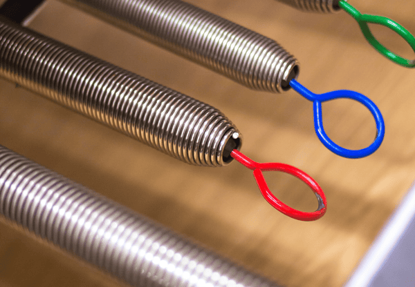 Close-up of metal tension springs with colored loops at the ends (red, blue, green).