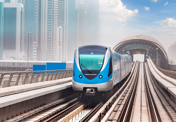 Modern blue and white train on an elevated track in an urban setting.