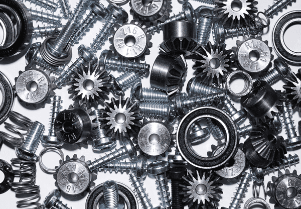 Assorted metal gears and screws scattered on a surface.