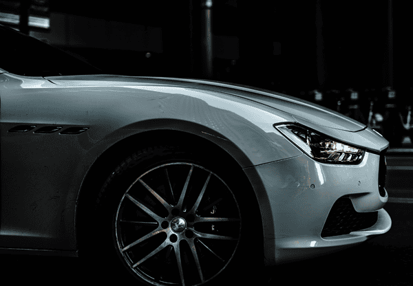 Close-up of the front side of a silver car at night.