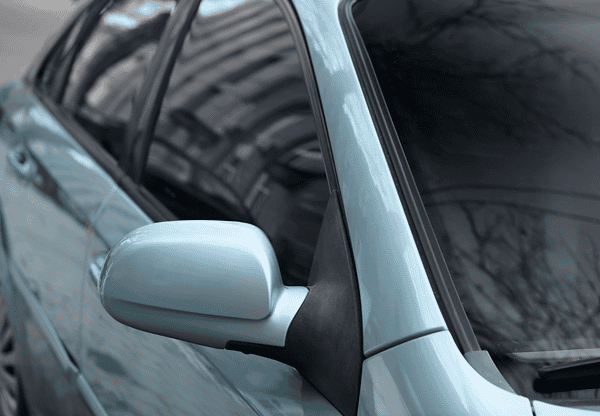 Close-up of a blue car's side mirror and windows.