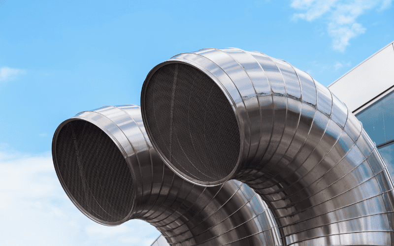 Large stainless steel ventilation pipes against a blue sky.