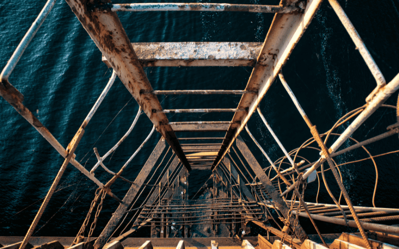 Rusty ladder descending into the water, in need of replacement with stainless steel.