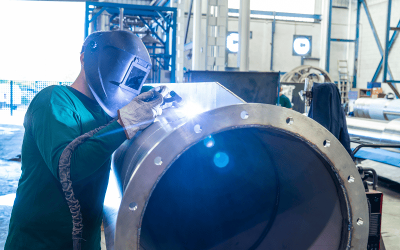 Trabajador soldando un tubo de acero inoxidable.