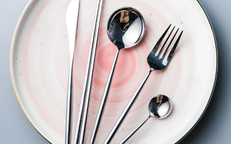 There are some cutlery on a pink plate.