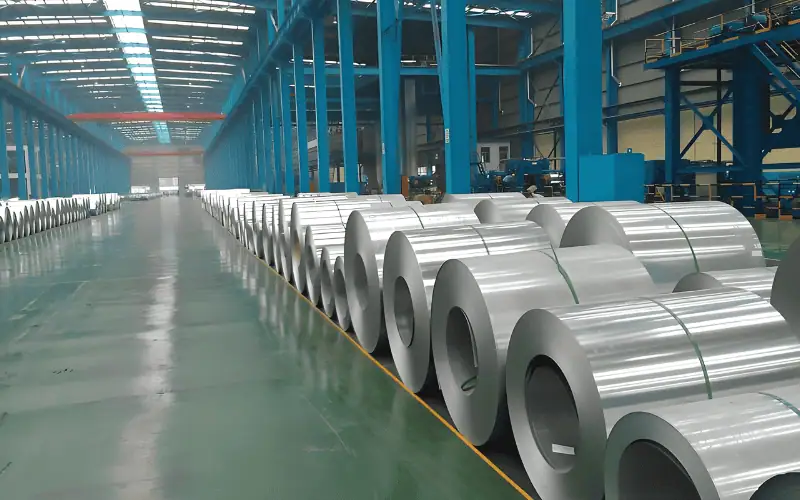 A warehouse storing large rolls of galvanized metal coils, commonly used in the steel industry.