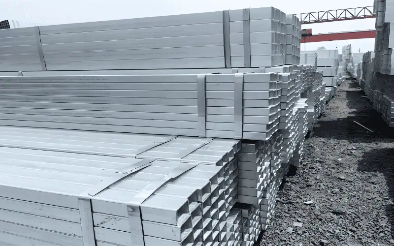 Stacks of hot dip galvanized rectangular pipes in an outdoor storage area.