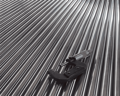 Stack of shiny cold rolled steel bars with measuring tools on top.