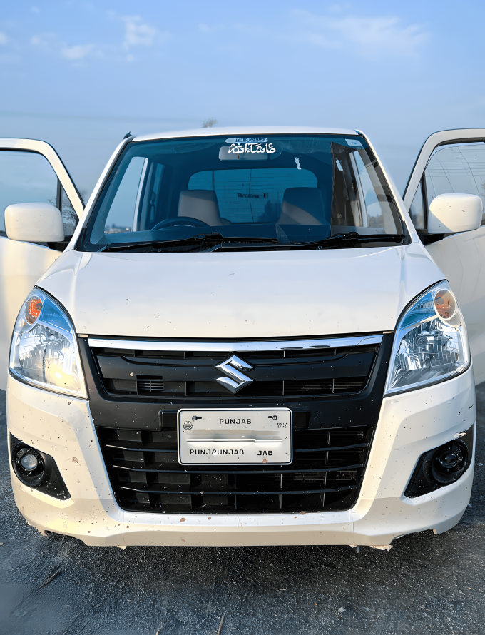 A white Suzuki car with its front doors open, parked outdoors on a gravel surface.