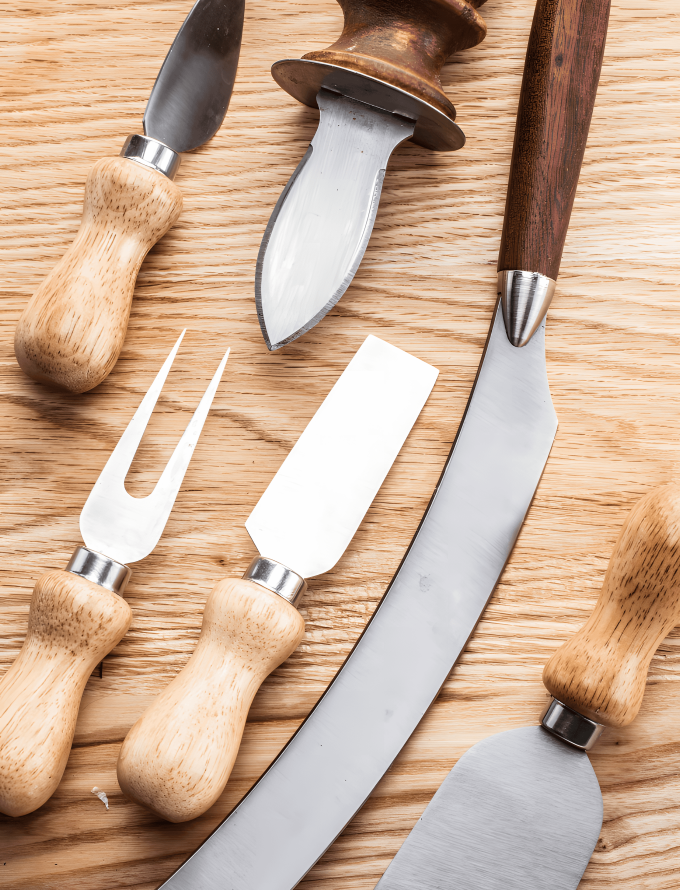 Various kitchen tools made from tool steel bars on a wooden surface.