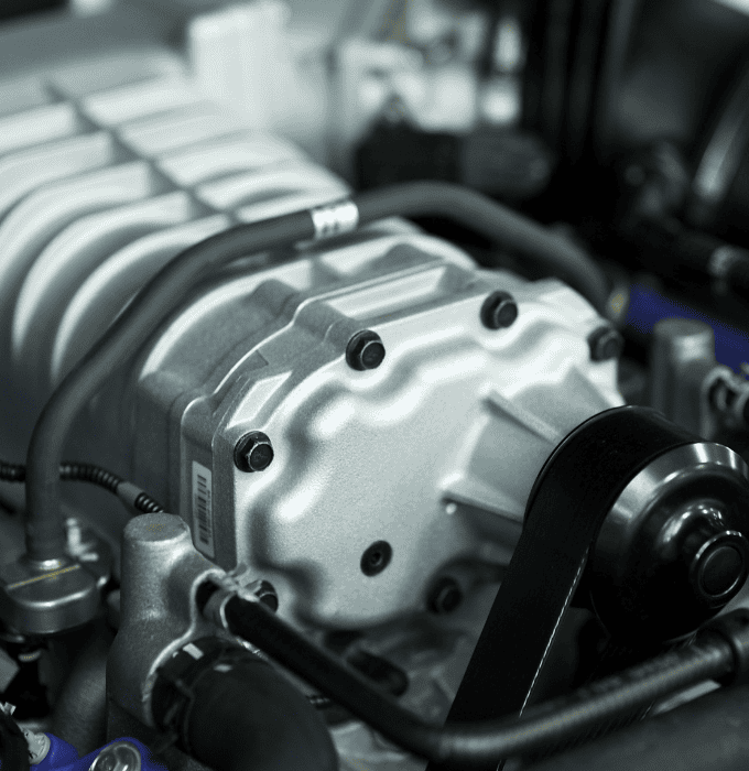 Close-up of a car engine component with visible bolts and belts.