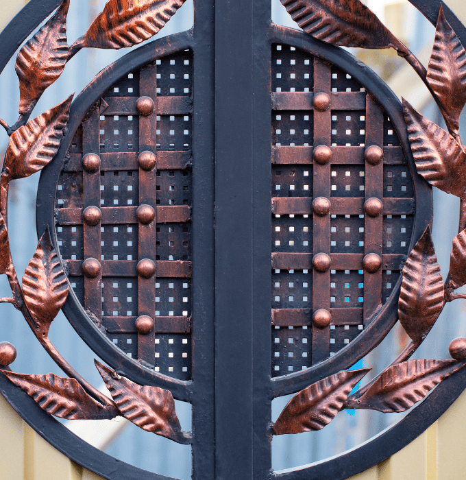 A decorative metal gate featuring an intricate circular design with copper leaves.