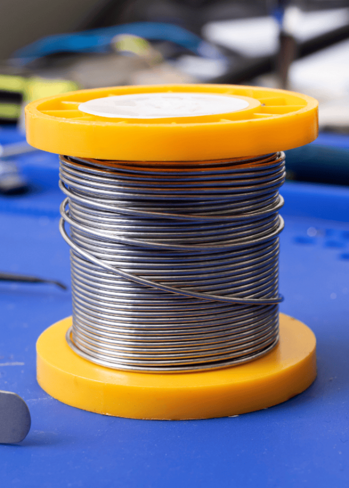 A spool of metal wire with an orange base and top.