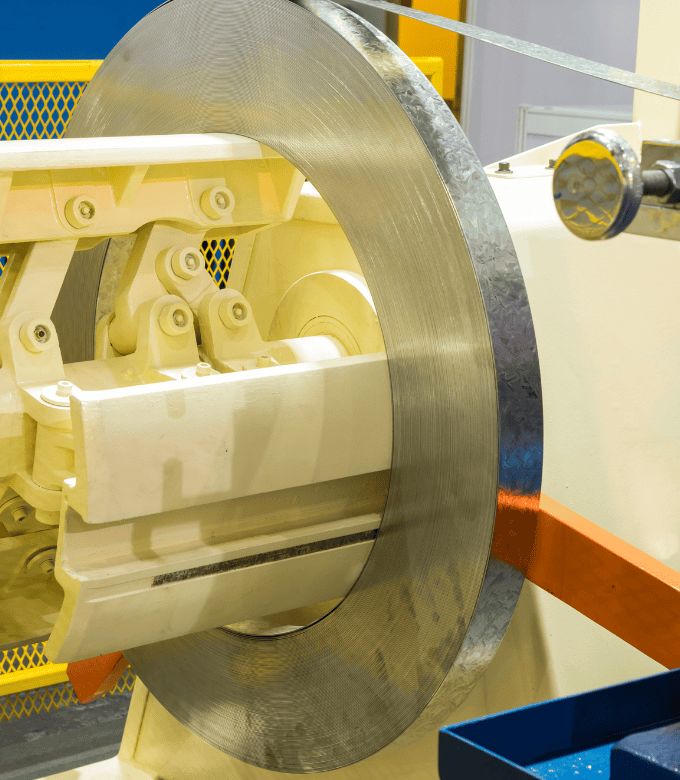 A large roll of steel being processed in an industrial machine.