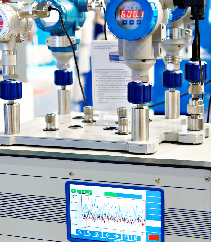 An industrial control panel with digital gauges and a display screen showing data graphs.