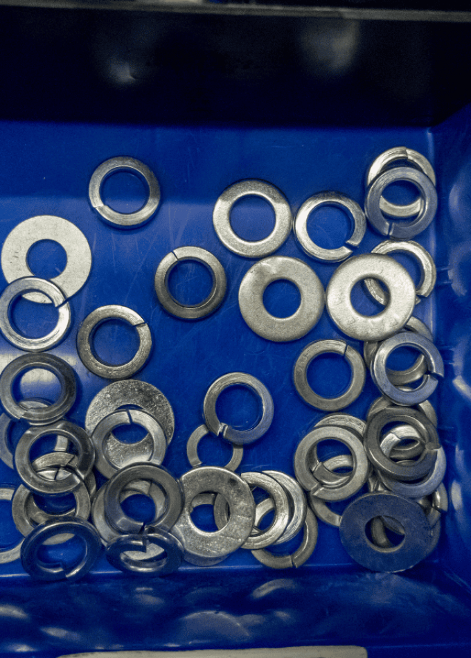 Assorted metal washers in a blue container.