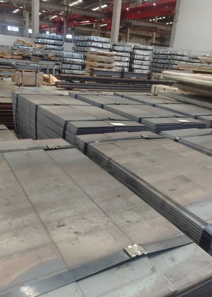 Piles of Cold Rolled Steel sheets stacked securely in a manufacturing plant.