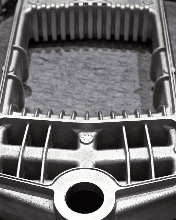 Close-up of a metal component with ribbed edges and a circular opening at the bottom.