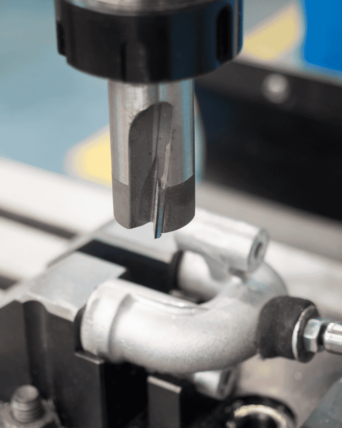 A metal component being drilled by a milling machine.