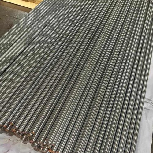 A large collection of thin, cylindrical high strength steel bars laid neatly side by side on a flat surface.