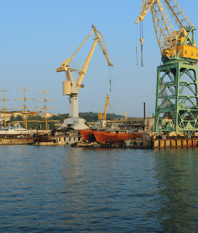 A view of a shipyard with cranes and docked ships, illustrating the importance of high strength steel bars in maritime construction and heavy machinery.