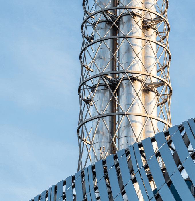 Close-up of a tall industrial structure with metal pipes and lattice framework.