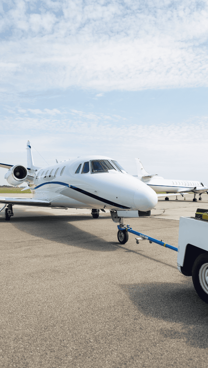 Small private jet being towed on an airport tarmac.