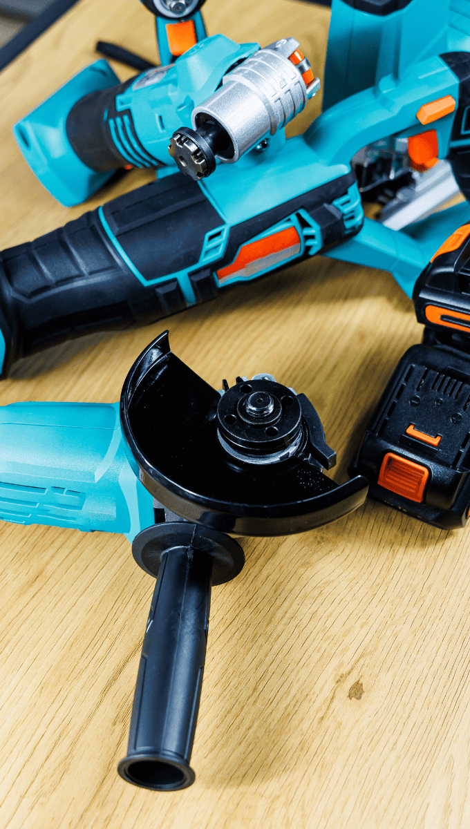 Assorted teal and black power tools on a wooden surface.