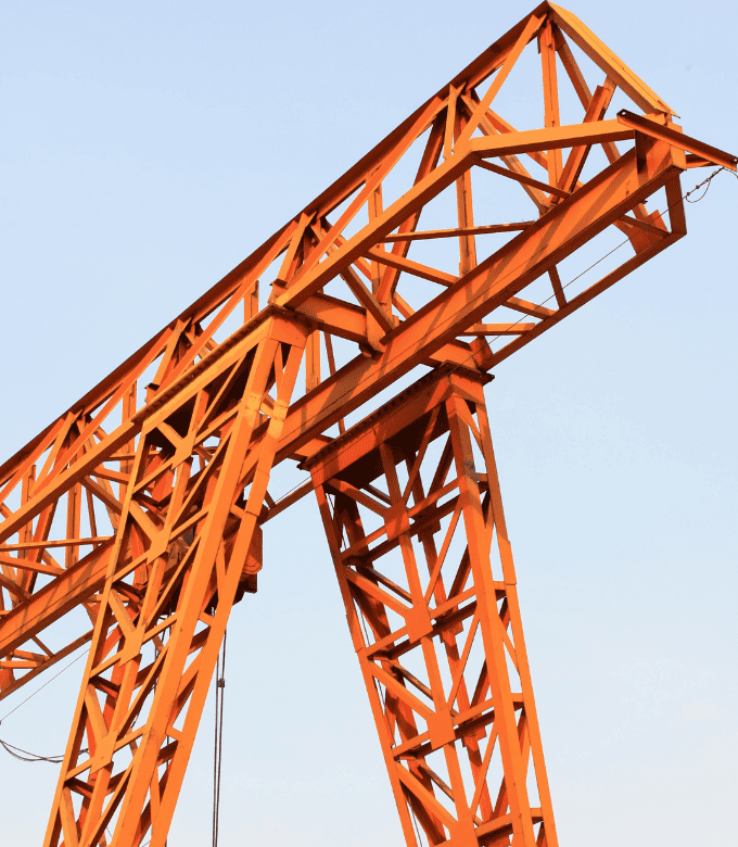 An orange steel structure with intricate lattice design stands against a clear sky.